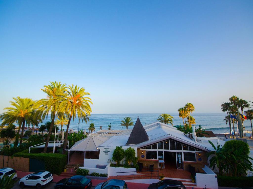 une maison sur la plage avec des palmiers et l'océan dans l'établissement Apartamento Vistamar, à Marbella