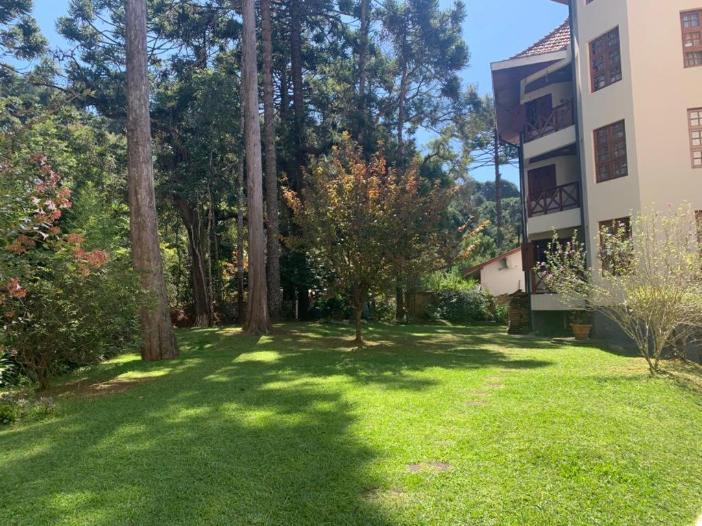 a yard in front of a building with trees at Apartamento lindo e aconchegante em Capivari. in Campos do Jordão