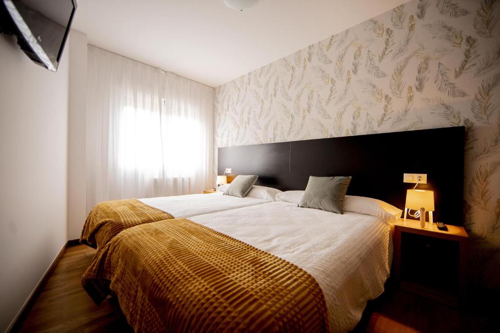 a bedroom with a large bed and a window at Cantares-NOJA ROOMS in O Pedrouzo