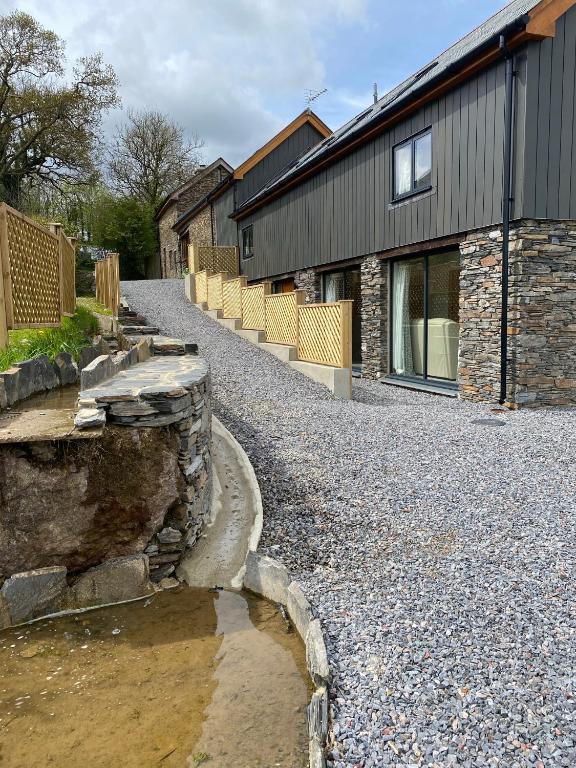 a house with a gravel road next to a building at Creber Cottage in Totnes
