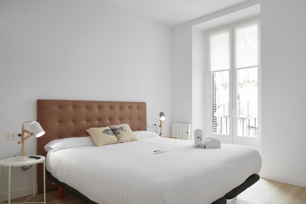 Un dormitorio con una gran cama blanca y una ventana en Etxaide - Basque Stay, en San Sebastián