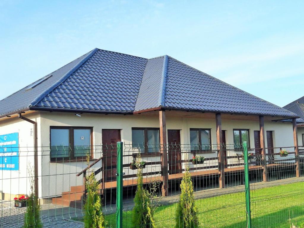 dom z niebieskim dachem i płotem w obiekcie Apartamenty Ster Darłówko w Darłówku