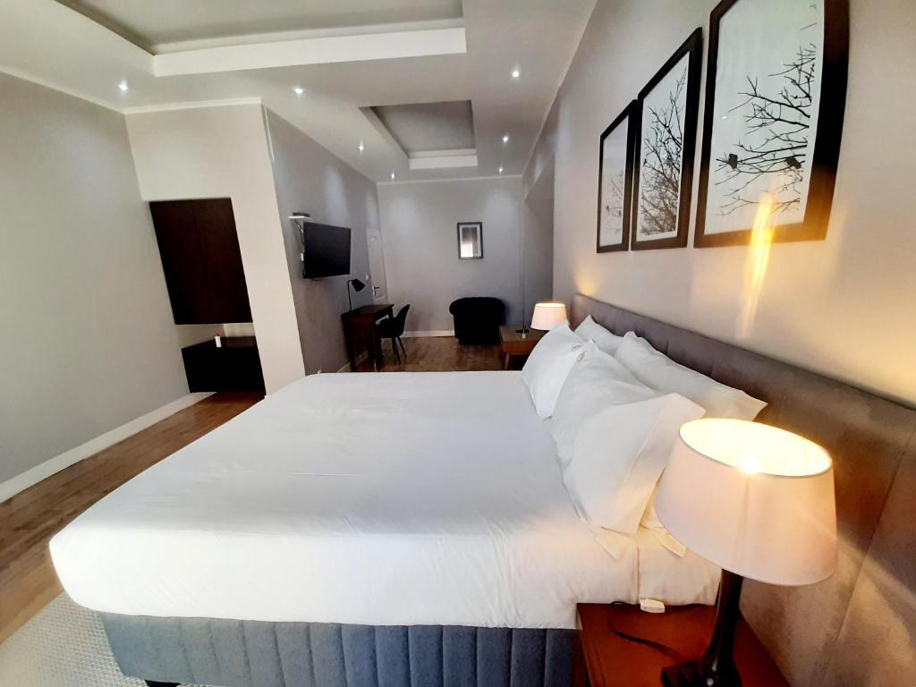 um quarto de hotel com uma cama grande com lençóis brancos em Terra Guest House em Maputo