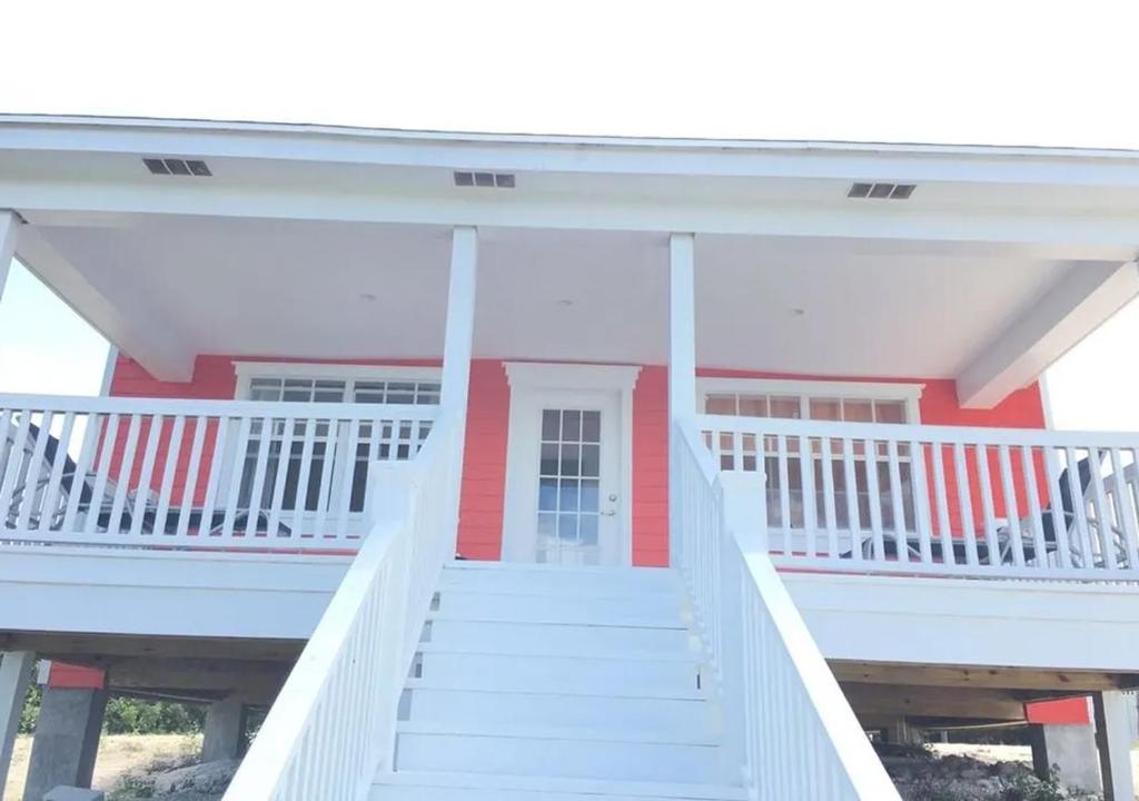 a red and white house with white stairs at Mangrove Cay Sea View Villas in Behring Point