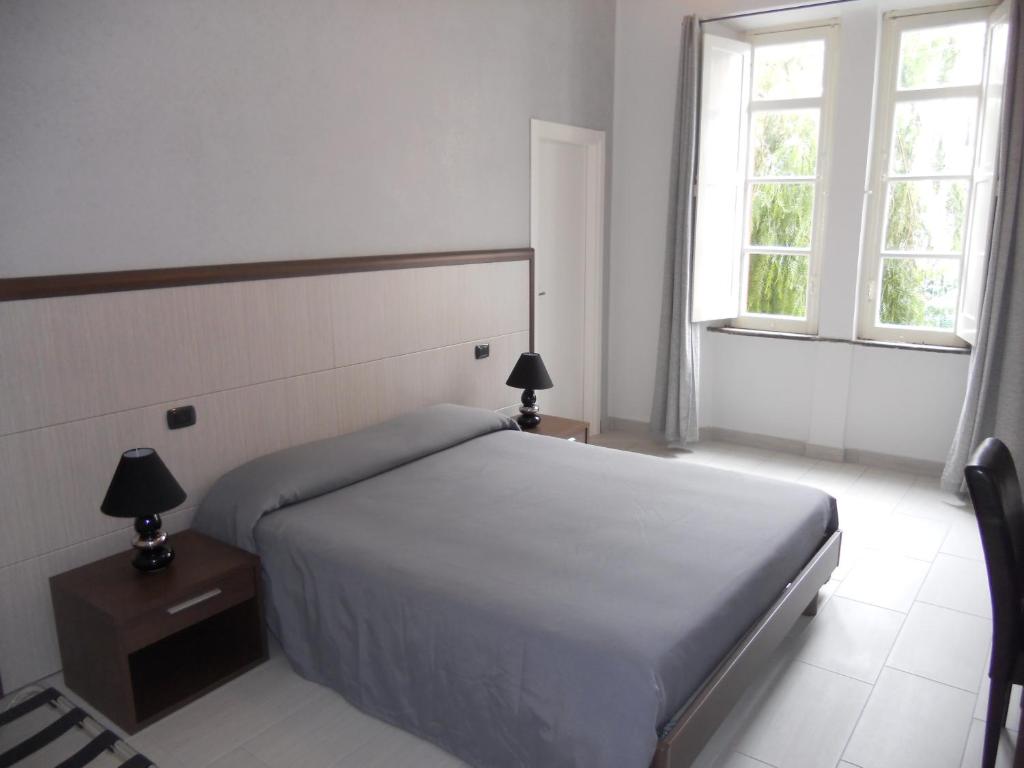 una camera bianca con un letto e due finestre di Sant'Agostino Affittacamere a Reggio di Calabria