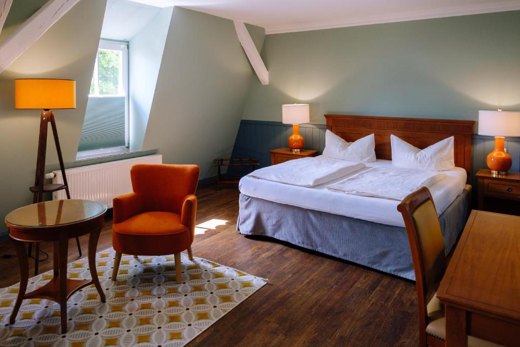 a bedroom with a bed and a table and a chair at SCHULZENS Brauerei & Hotel in Tangermünde