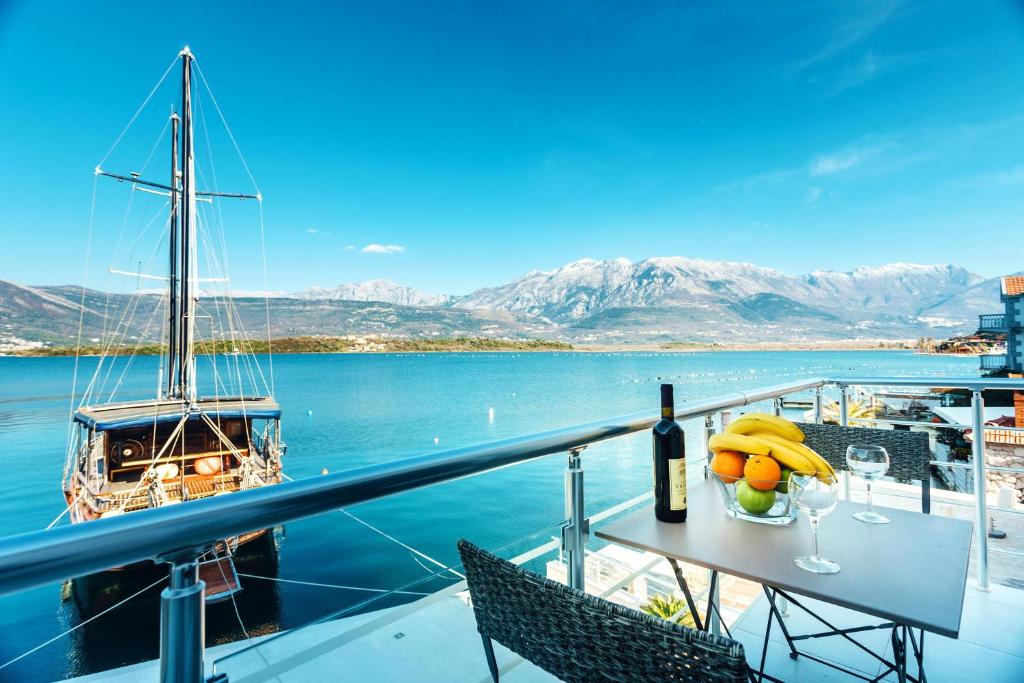 einen Tisch mit Obst, eine Flasche Wein und ein Boot in der Unterkunft Beachfront Apartments Tivat in Tivat