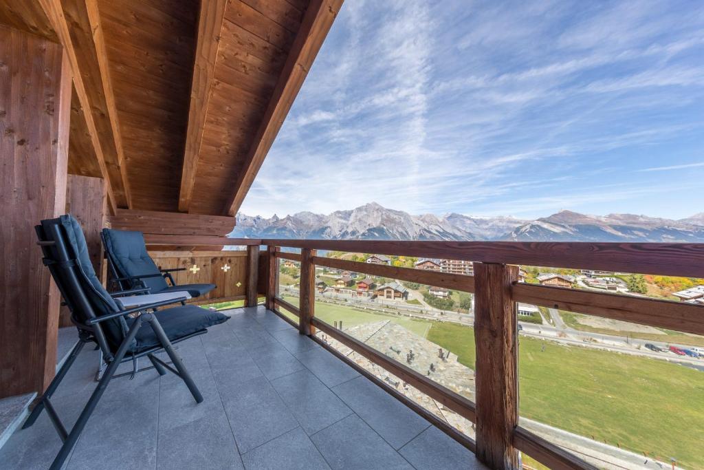 a balcony with two chairs and a view of mountains at Montagnard 12 - spa access - car and careless holidays! in Nendaz