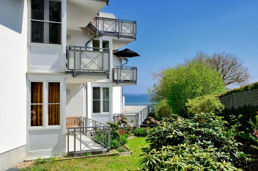 a white house with balconies and the ocean in the background at Ferienwohnung Hafenliebe, Villa Vilmblick mit Meerblick in Lauterbach