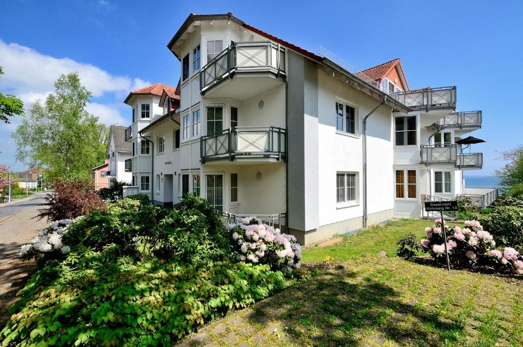 une grande maison blanche avec des fleurs devant elle dans l'établissement Ferienwohnung Hafenglück, Villa Vilmblick, à Lauterbach