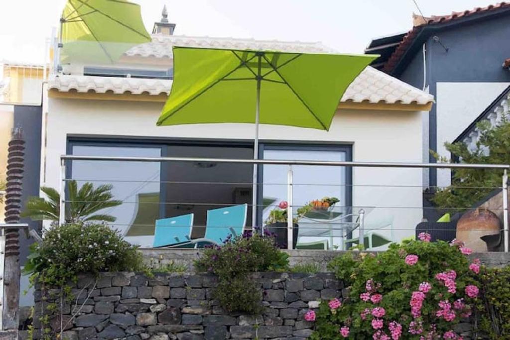 a green umbrella in front of a house at Crystal House in Calheta