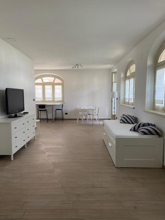 um grande quarto branco com uma cama e uma televisão em Coronata 22 em Fossano