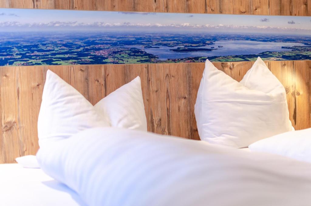 a bed with white pillows on a wooden wall at Gasthof Messerschmied in Rottau