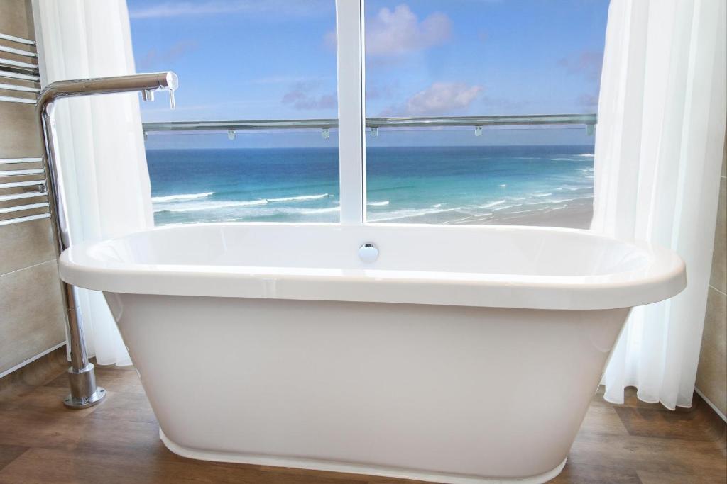 a bathroom with a bath tub and a window with the ocean at Esplanade Hotel in Newquay