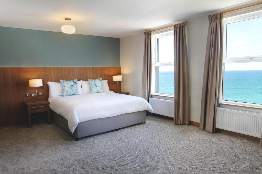 a bedroom with a bed and two windows at Esplanade Hotel in Newquay