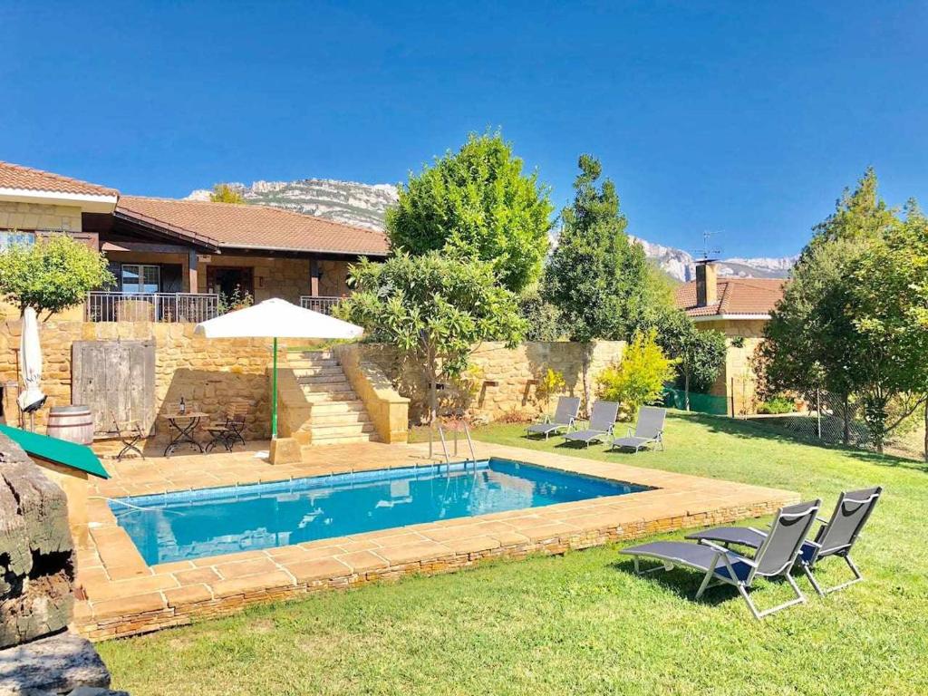 una piscina en un patio con sillas y sombrilla en SagastiEnea Villa con Piscina y Tenis en la Rioja en Samaniego