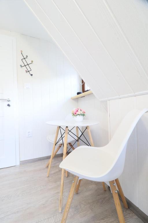 a white dining room with a white chair and stairs at Pension Adel in Český Krumlov