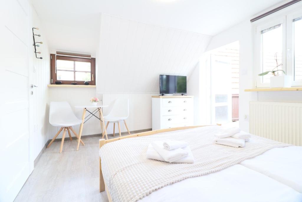 a white bedroom with a bed and a tv at Pension Adel in Český Krumlov