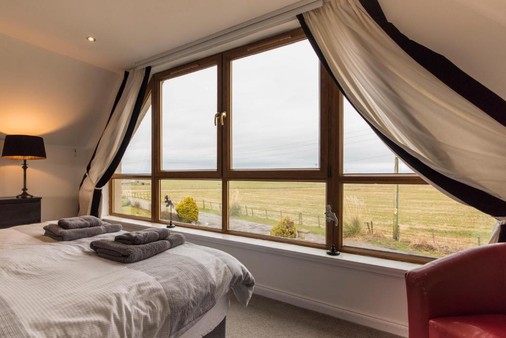 a bedroom with a bed and a large window at Valleyview House in Thurso