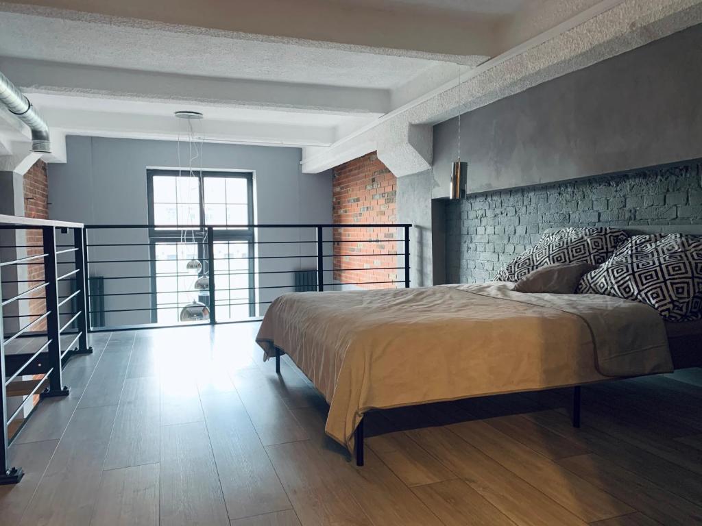 a bedroom with a large bed with a brick wall at Loft De Girarda in Żyrardów