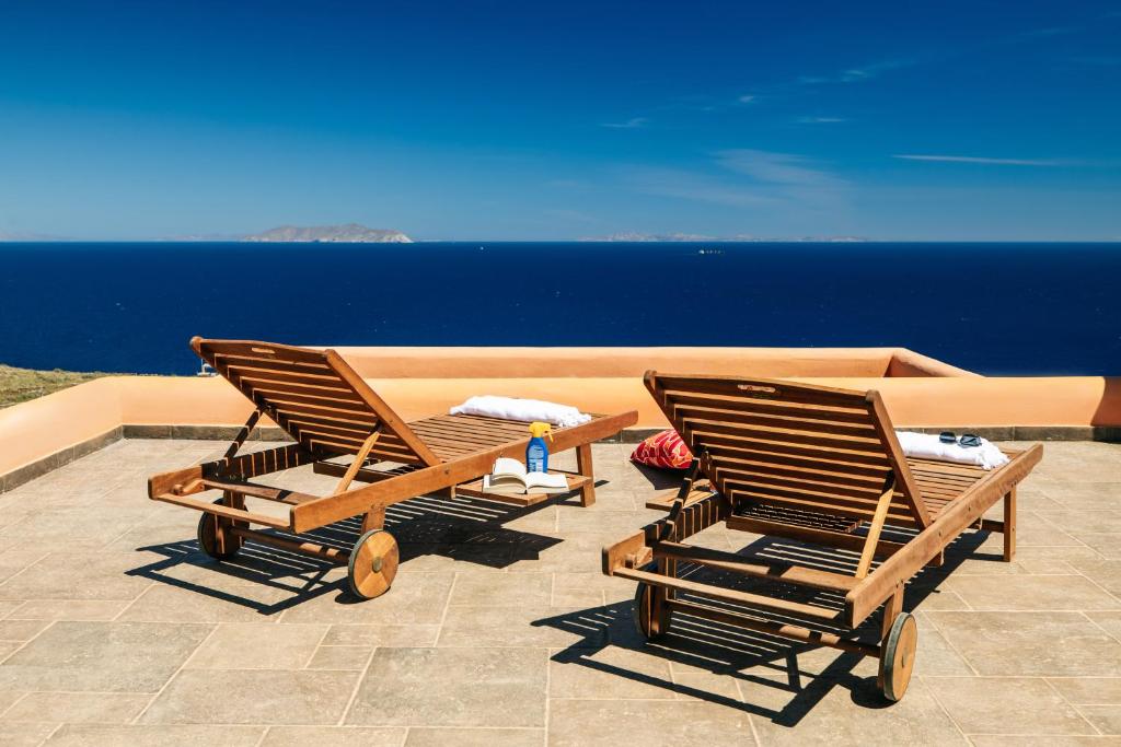 Duas espreguiçadeiras sentadas num pátio com vista para o oceano em Front Row Seat to the Aegean by Neuvel em Ioulida