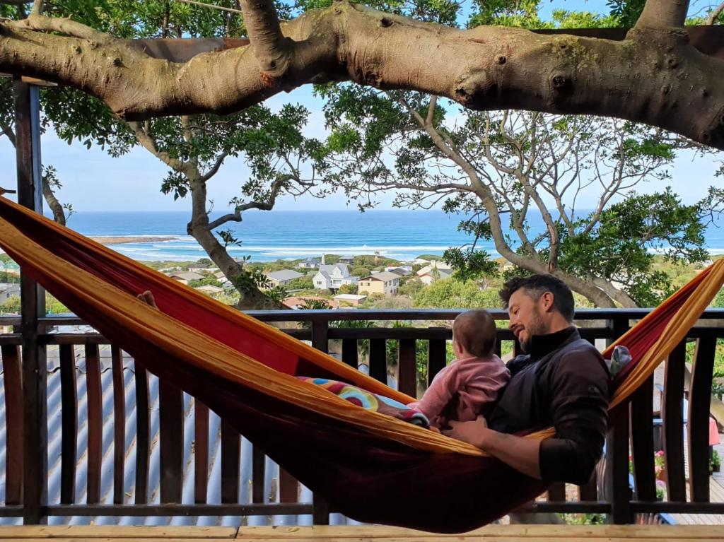 a man and a baby sitting in a hammock at Scarborough Nature Lodge in Cape Town