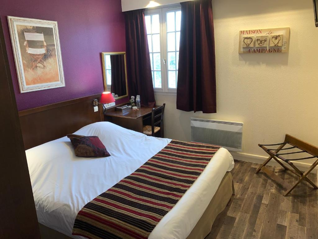 a bedroom with a bed and a desk and a window at Hôtel Les Nymphéas in Chaufour-lès-Bonnières