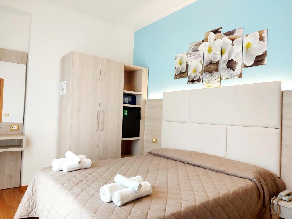 a bedroom with two white towels on a bed at Hotel Monica in Rimini