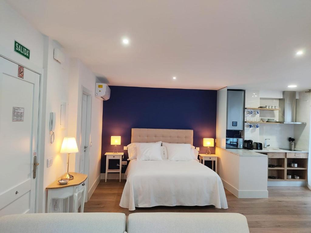 1 dormitorio con cama blanca y pared azul en AT La casa Azul en Cuenca