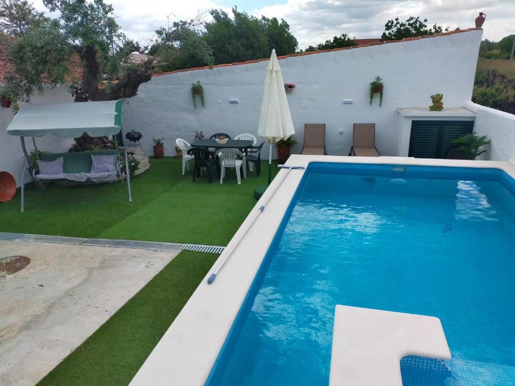 einen Pool im Hinterhof mit einem Tisch und einem Tisch in der Unterkunft Casa da Avó Rita in São Pedro do Corval