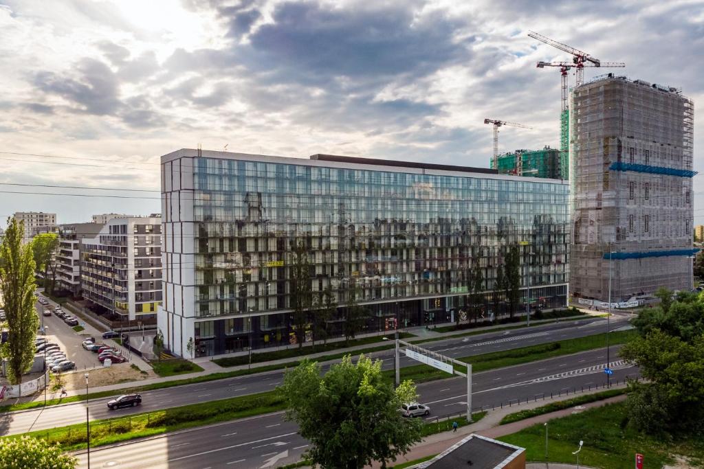 un grand bâtiment en verre dans une ville avec une rue dans l'établissement Warsaw Apartments Prymasa Street, à Varsovie