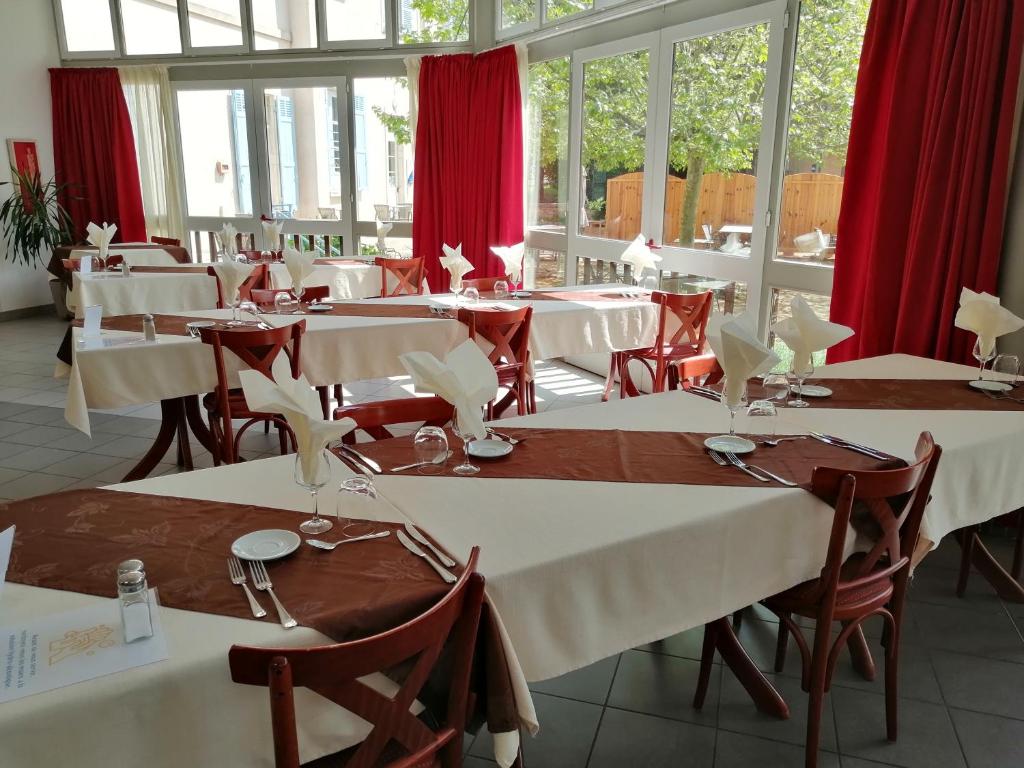un restaurante con mesas, sillas y cortinas rojas en VTF Le Domaine Les Hautannes, en Saint-Germain-au-Mont-dʼOr