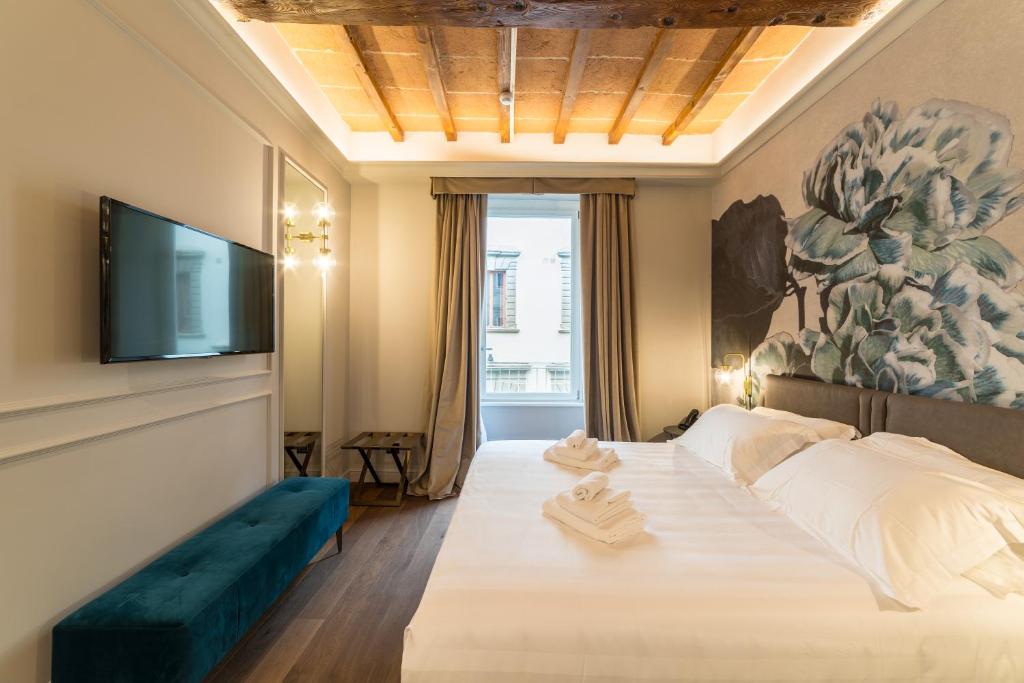 a bedroom with a large bed and a flat screen tv at Palazzo 42 - Boutique Hotel & Suites in Pistoia