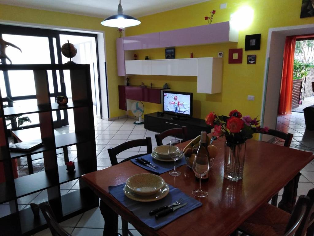 una sala da pranzo con tavolo e TV di Appartamento Asia a Città di Lipari
