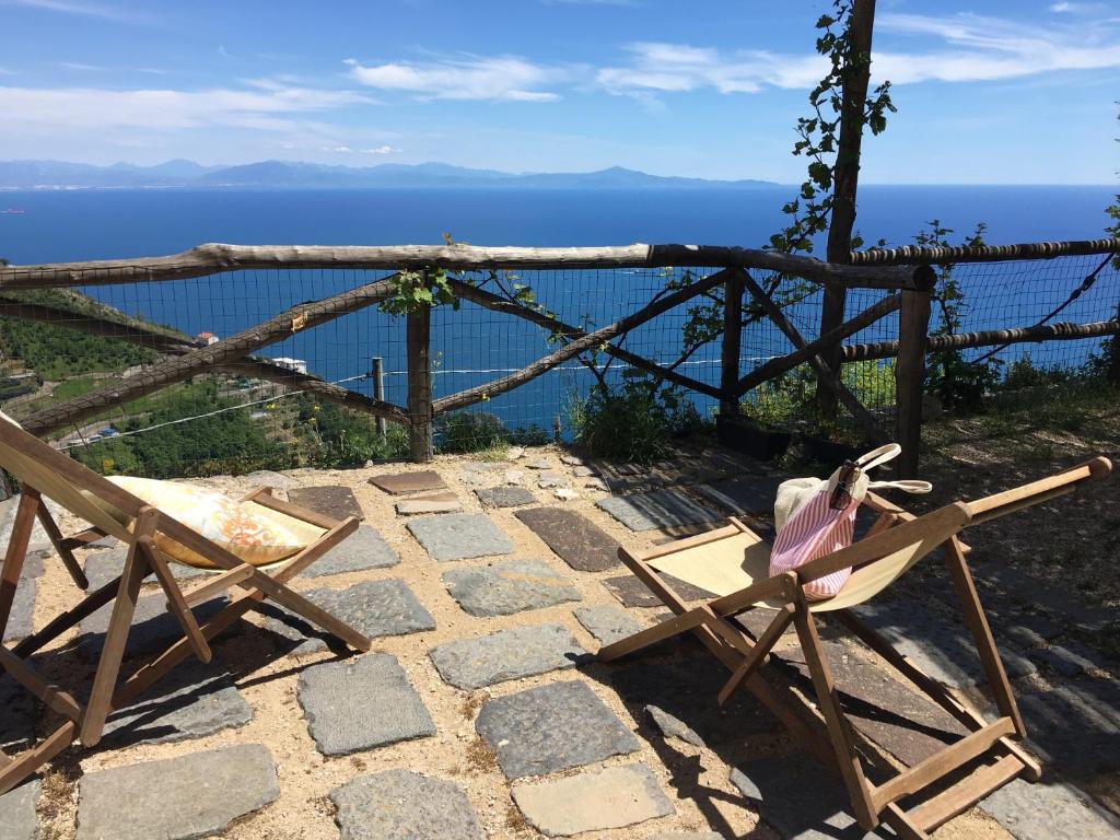 a pair of chairs sitting on a stone patio overlooking the ocean at Il Nido Del Falco - Art house with terrace and sea view in Furore