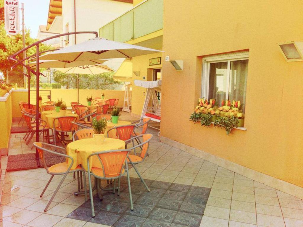 een patio met tafels en stoelen en een parasol bij Hotel Zenit in Riccione