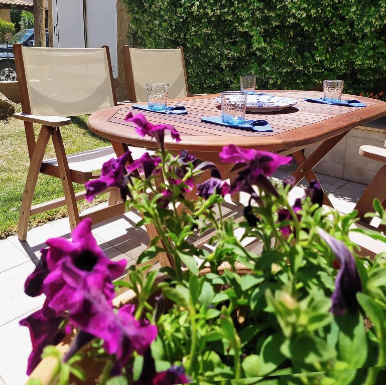 a wooden table and chairs and purple flowers at Seaside Villa Clio in Skála Nikíta