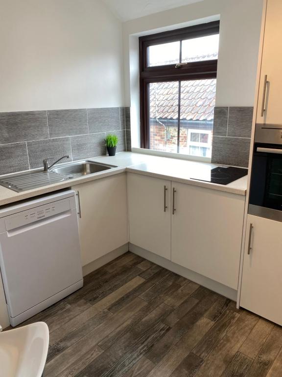 a kitchen with white cabinets and a sink and a window at 1st Floor Flat in Mews in Kessingland