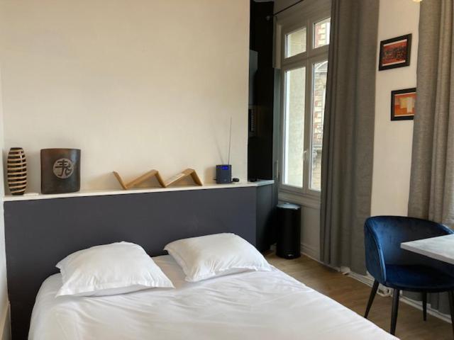 a bedroom with a white bed and a blue chair at Le Select Studio in Dieppe