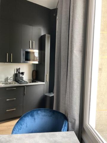 a blue chair in a room with a kitchen at Le Select Studio in Dieppe
