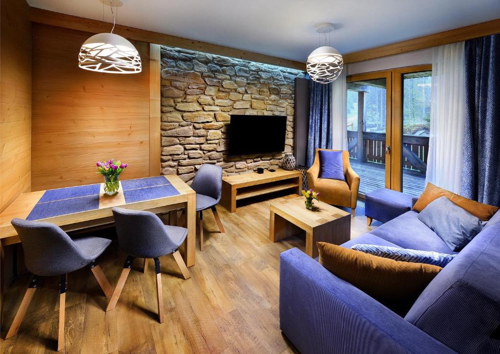 a living room with a blue couch and a stone wall at Chalety Horská Lúka Jasná SKI IN & SKI OUT in Belá