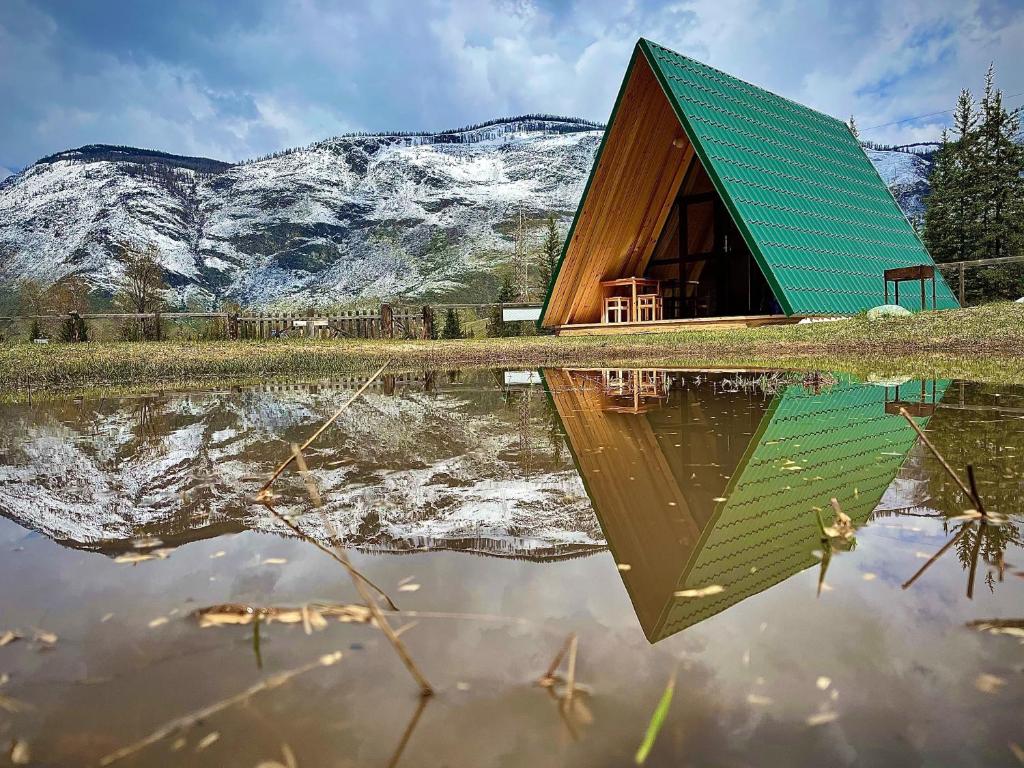 a house with a green roof reflected in a body of water at Eco-turbaza Green Kolobok in Aktash