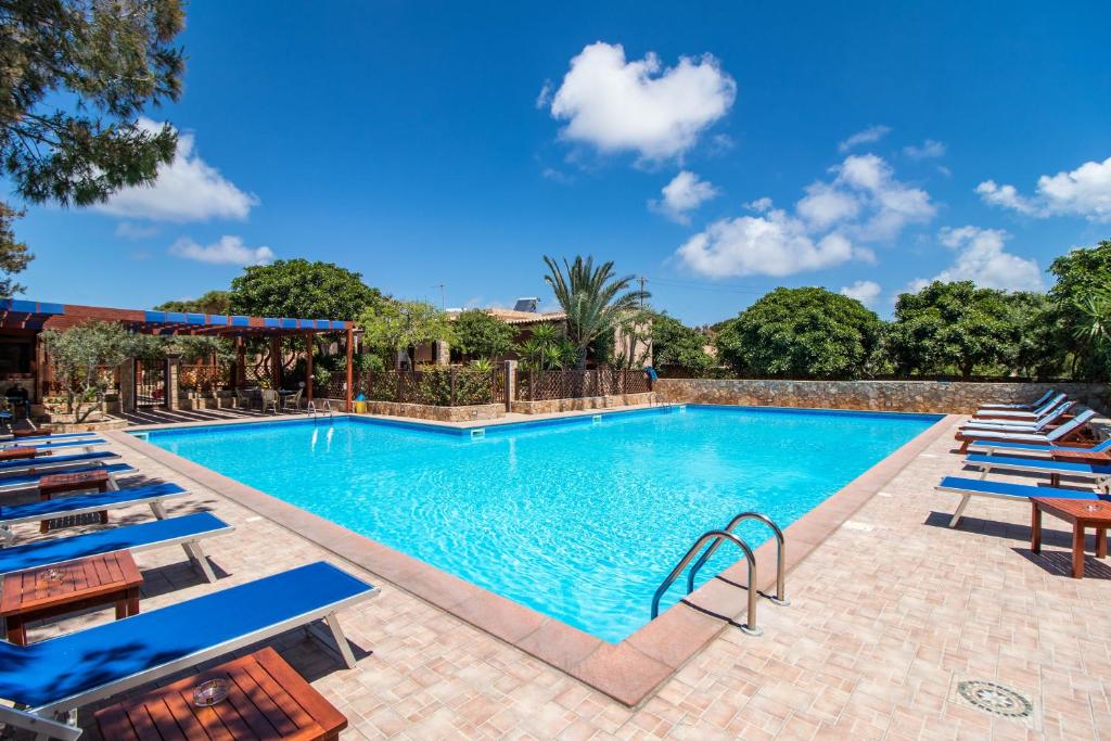 una piscina con sedie a sdraio blu e un resort di Residence Villalba a Lampedusa