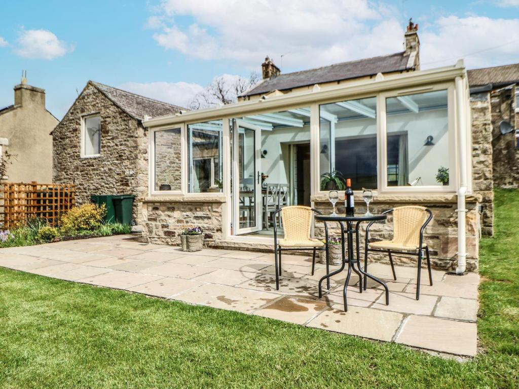 an extension to a stone house with a table and chairs at West Reins in Barnard Castle