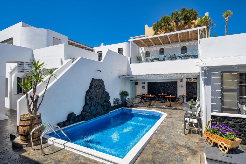 a villa with a swimming pool in front of a house at Plastiras Rooms in Fira