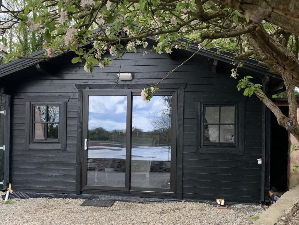un cobertizo negro con una gran puerta de cristal en The Cosy Cabin by the shore en Galway