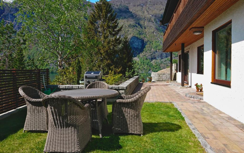 a patio with a table and chairs on the grass at Otnes Fjordside in Aurland