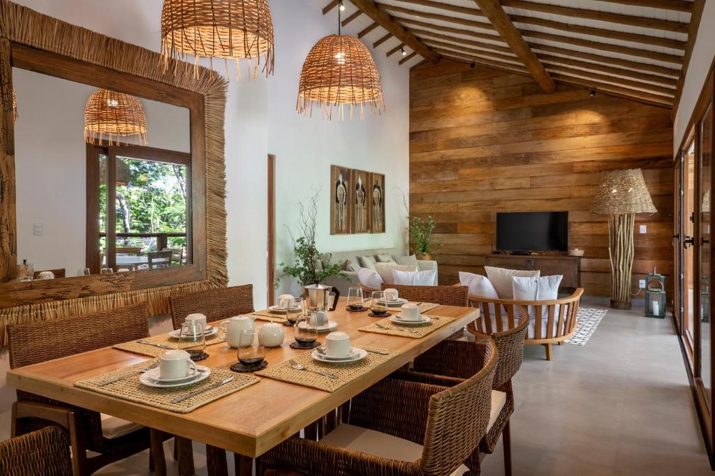 ein Esszimmer mit einem großen Holztisch und Stühlen in der Unterkunft Flamboyant Residence Quadrado in Trancoso