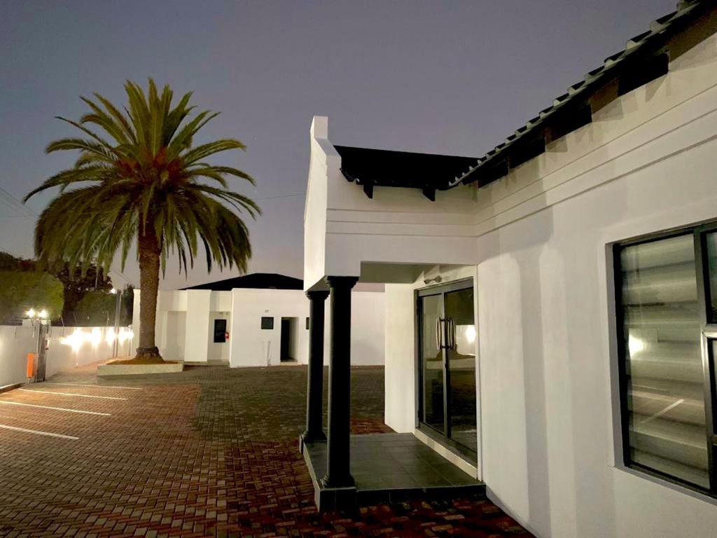 Randfontein的住宿－Thamani Guest House，一座白色的建筑,前面有棕榈树