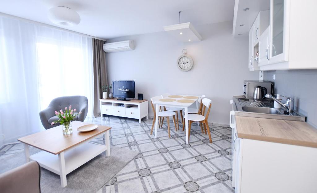 uma cozinha e uma sala de estar com mesa e cadeiras em Wolski Apartments - Reymonta 15 em Kolobrzeg